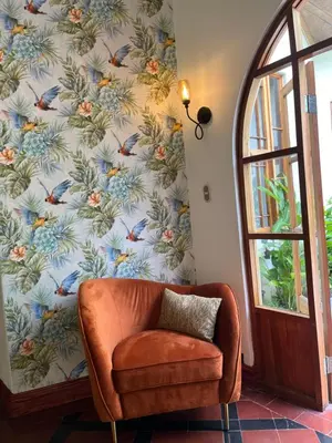 a chair in front of a wall with a floral wallpaper at The Victorian Hotel in San José
