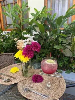 a table with a glass of wine and flowers on it at The Victorian Hotel in San José