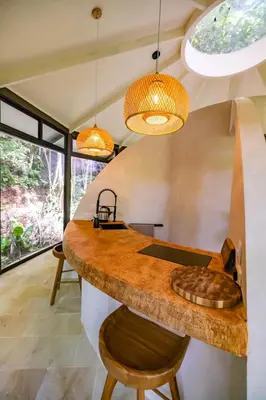 an open kitchen with a large wooden counter and some lights at The Nest Unique Jungle Retreat in Barú