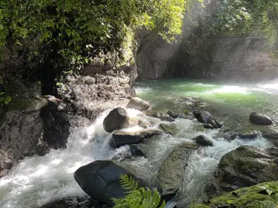 a river with green water and rocks in a canyon at The Nest Unique Jungle Retreat in Barú