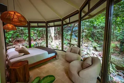 a bedroom with a bed and chairs in a forest at The Nest Unique Jungle Retreat in Barú