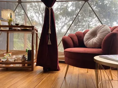 a living room with a red couch and a large window at The SAFIRA Dome at FéLIZA Rainforest Domes in Monteverde Costa Rica