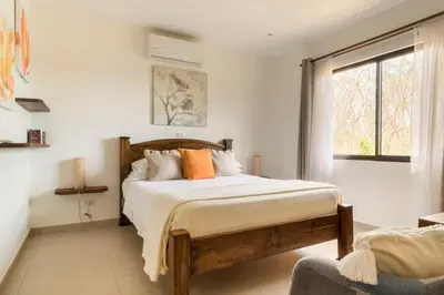 a bedroom with a bed with orange pillows and a window at Green Villas Tamarindo in Tamarindo
