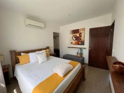 a bedroom with a bed with yellow and white pillows at Green Villas Tamarindo in Tamarindo