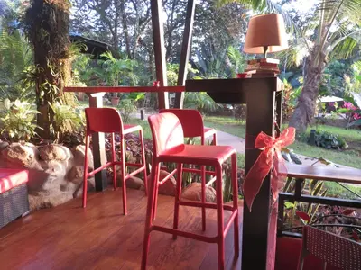 a porch with red chairs and a table with a bow at Oasis de las Palmas in Ojochal