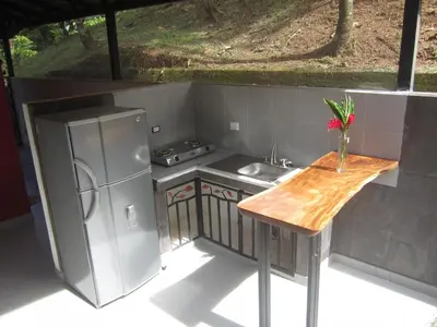 a kitchen with a table and a refrigerator and a sink at Oasis de las Palmas in Ojochal