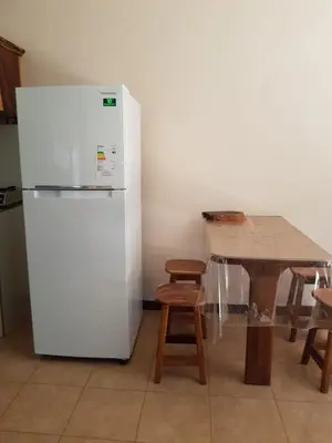 a kitchen with a white refrigerator and a table at Cabinas en Playas del Coco in Sardinal