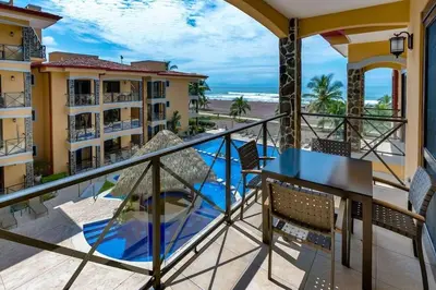 a balcony with a table and chairs and a view of the beach at Jaco Beachfront Oasis Newly renovated dream condo in Jacó