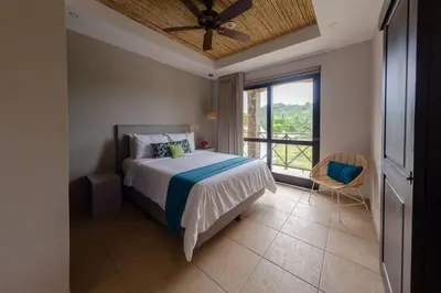 a bedroom with a bed and a large window at Jaco Beachfront Oasis Newly renovated dream condo in Jacó