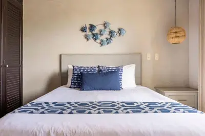 a bedroom with a large bed with a blue pillow at Jaco Beachfront Oasis Newly renovated dream condo in Jacó