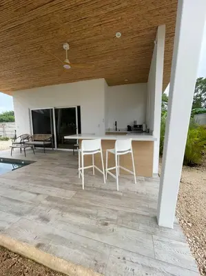 a patio with two white chairs and a table at Antemar Guest, Beach bungalow near Conchal in Brasilito