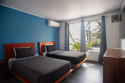 two beds in a room with a window at Casa Plata - 10 bed, 5 bdrm - One Block from Clubs in Jacó
