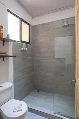 a bathroom with a toilet and a glass shower at Casa Plata - 10 bed, 5 bdrm - One Block from Clubs in Jacó