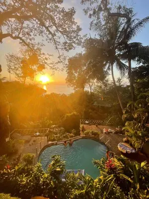a view of a pool with the sunset in the background at Mango Moon Villa in Manuel Antonio