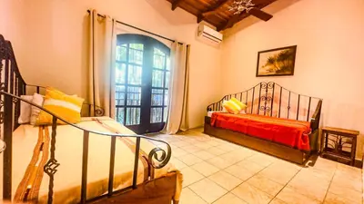 a bedroom with a bed and a large window at Mango Moon Villa in Manuel Antonio