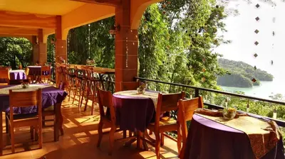 a restaurant with tables and chairs on a balcony at Mango Moon Villa in Manuel Antonio