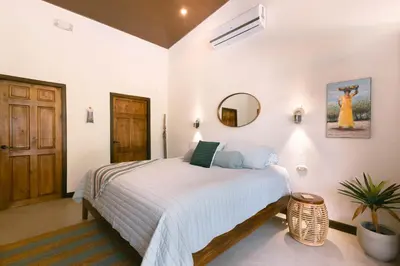 a white bedroom with a bed and a mirror at Jungle Glory Home Arriba in Manuel Antonio