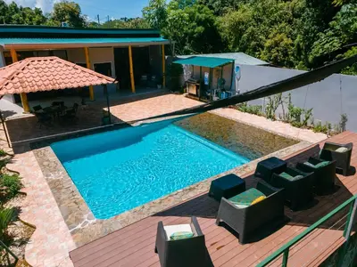 a swimming pool with chairs and a house at Jungle Glory Home Arriba in Manuel Antonio