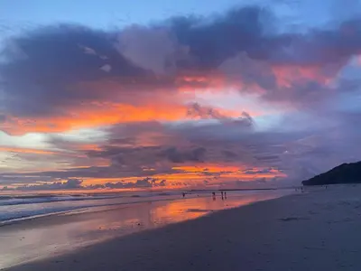 a sunset on a beach with people walking on the sand at Casa VISTA PARAISO - Vista al mar - Selva - WIFI - Deck Yoga - Sunset in Santa Teresa Beach