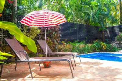 two chairs and an umbrella next to a pool at 3 minutes walk from the best surf beach in area in Dominical