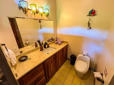 a bathroom with a sink and a toilet and a mirror at 3 minutes walk from the best surf beach in area in Dominical