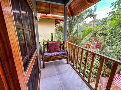 a wooden porch with a chair on a balcony at 3 minutes walk from the best surf beach in area in Dominical