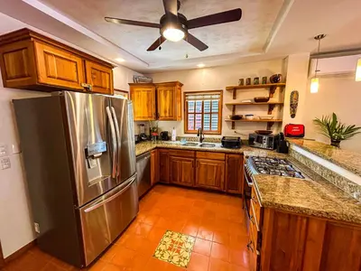 a kitchen with a stainless steel refrigerator and wooden cabinets at 3 minutes walk from the best surf beach in area in Dominical