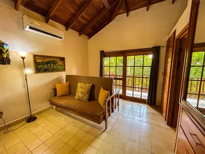 a living room with a couch and some windows at 3 minutes walk from the best surf beach in area in Dominical
