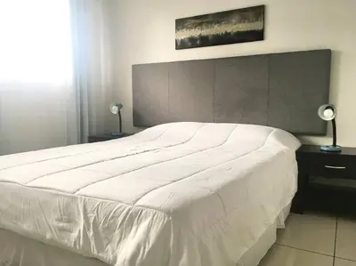 a large white bed in a bedroom with two lamps at Conveniente ubicación en zona muy silenciosa Apt 3 in Curridabat