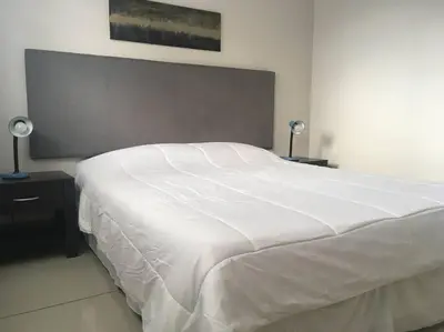 a large white bed in a bedroom with two lamps at Conveniente ubicación en zona muy silenciosa Apt 3 in Curridabat