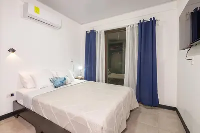 a bedroom with a large white bed with blue curtains at Casa Serenity Arenal,Fully Equip in Fortuna