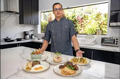 a man standing in a kitchen with plates of food at Volcano Lux Arenal in Fortuna