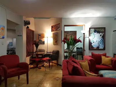 a living room with red couches and a dining room at Casa Echavarria in San José