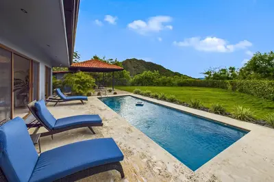 a swimming pool with two blue chairs and a house at Casa Tranquilo 26B - Beautiful Home With A Private Pool in Playa Flamingo