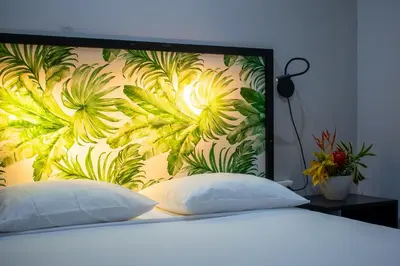 a bed with two pillows in front of a floral wall at Bukala Village Lodge in San Ramón