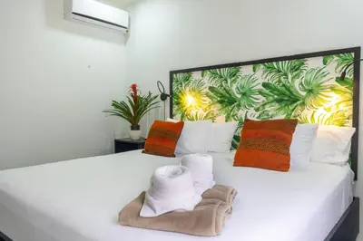 a bedroom with a large white bed with colorful pillows at Bukala Village Lodge in San Ramón