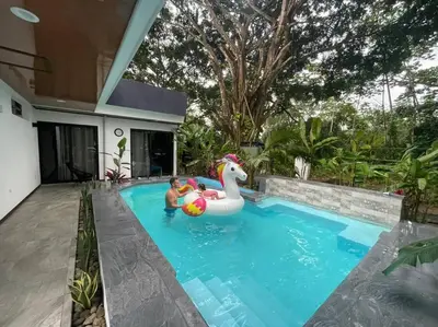 a man and a boy in a pool with a rubber duck in a swimming pool at Fortuna Jungle & River Retreat - Private pool, River and Wifi in the forest - Secluded, peaceful, truly UNIQUE! A GEM! Book Now! in Guayabal