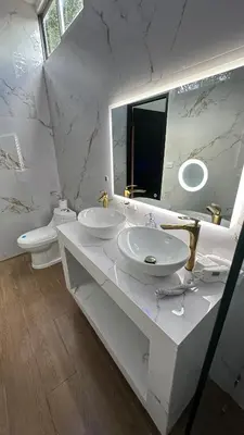 a white bathroom with two sinks and a mirror at H et L in Tortuguero