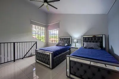 a bedroom with two beds and a ceiling fan at Villa Escondida La Fortuna in Fortuna