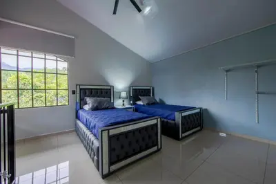 a bedroom with two beds with blue sheets and a window at Villa Escondida La Fortuna in Fortuna