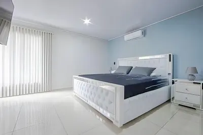 a white bedroom with a large white bed with blue sheets at Villa Escondida La Fortuna in Fortuna