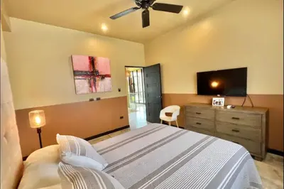 a bedroom with a bed with a ceiling fan and a dresser at Villas Confort Completas Manuel Antonio Kepos Costa Ric in Quepos