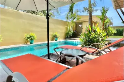 a swimming pool with tables and chairs and an umbrella at Villas Confort Completas Manuel Antonio Kepos Costa Ric in Quepos
