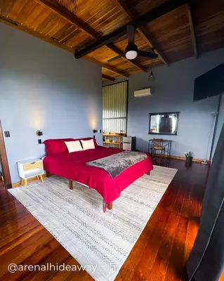 a bedroom with a red bed and a rug at Arenal Hideaway in San Ramón