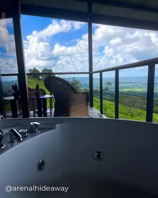 a bath tub in a room with a view at Arenal Hideaway in San Ramón
