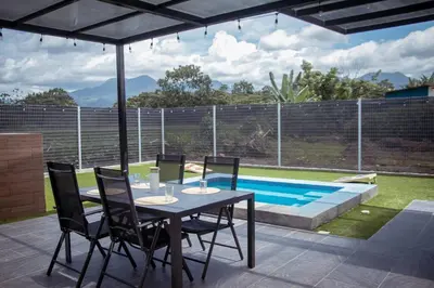 a table and chairs under an umbrella next to a swimming pool at La Fortuna Up House in Fortuna