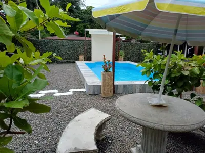 a table with an umbrella next to a swimming pool at Habitaciones Kolibri in Quepos