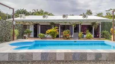 a swimming pool in front of a house at Habitaciones Kolibri in Quepos