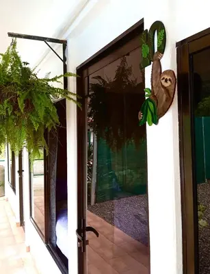 a sliding glass door with a sloth hanging on it at Habitaciones Kolibri in Quepos
