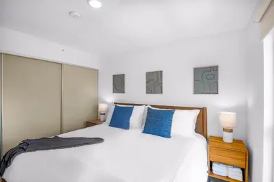 a bedroom with a large white bed with blue pillows at Upstay - New Condo in Jaco - 5 mins from Beach in Jacó